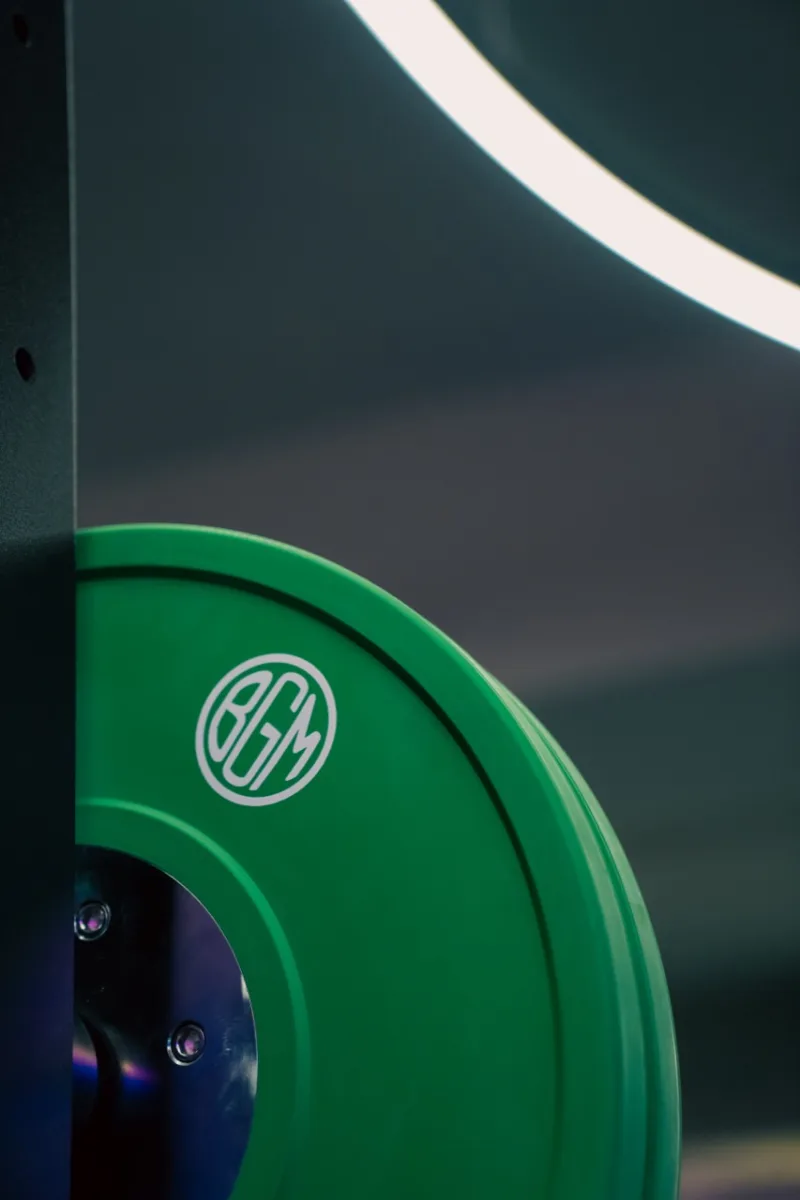 Green BGM weight plate photographed under a studio ring light